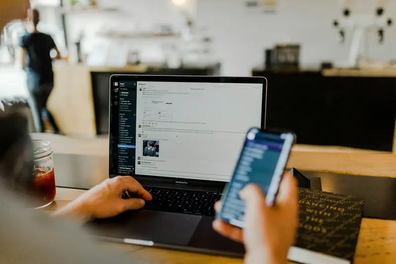 Person using a mobile app alongside a laptop