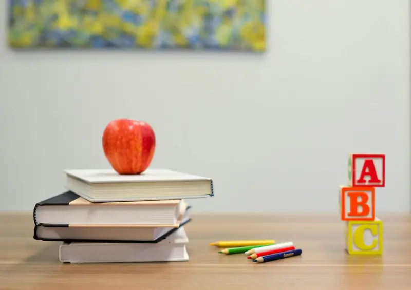 Books, an apple and alphabet blocks on a desk